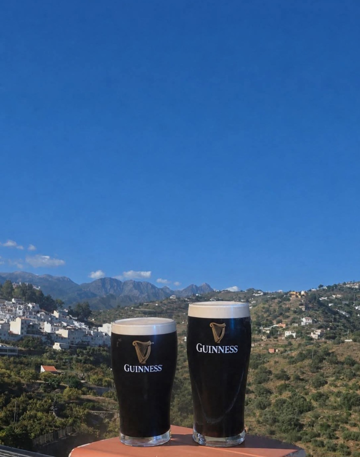 Two pints of draught Guinness overlooking Torrox Pueblo and the Málaga mountains